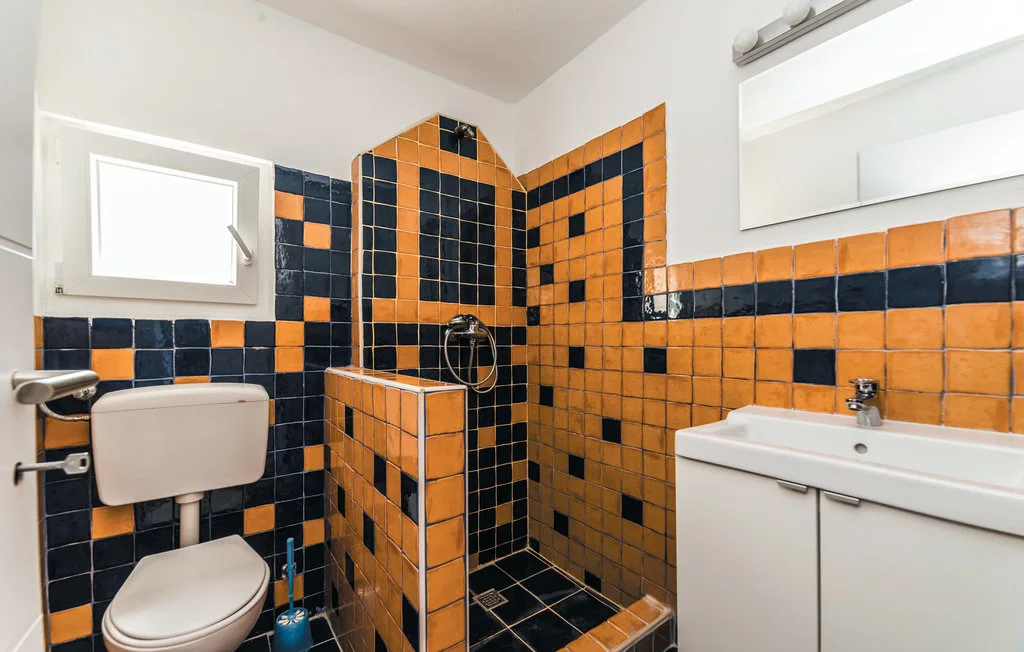 A bathroom with a tiled shower, toilet, and sink.