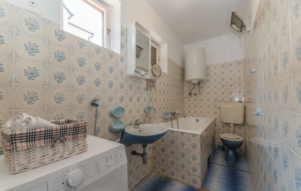 A tiled bathroom with a bathtub, sink, and washing machine.