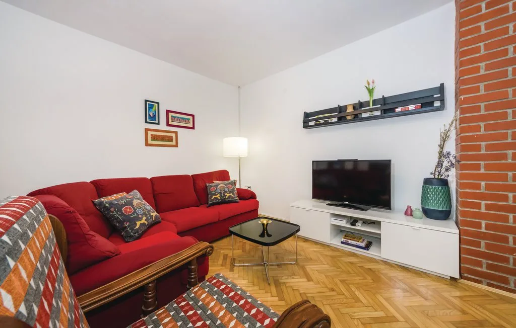 A living room with red seating, a television, and a glass coffee table.