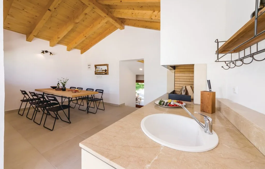An open dining and kitchen area with a table beneath a wooden ceiling.