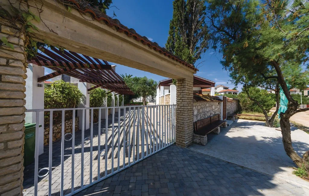 A gated outdoor entrance opens onto a paved courtyard with trees.