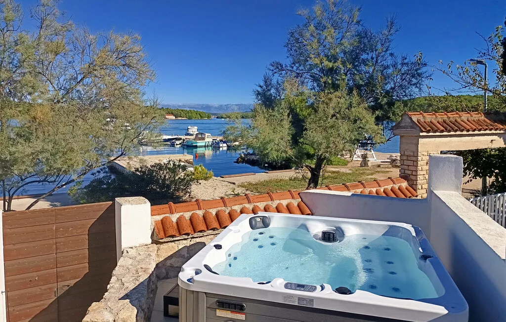 Outdoor hot tub overlooking a lake, with boats and trees in the background.