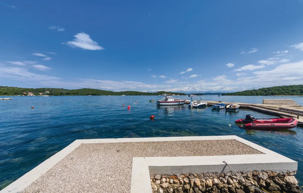 A waterfront landing overlooks calm blue water, with small boats moored nearby.