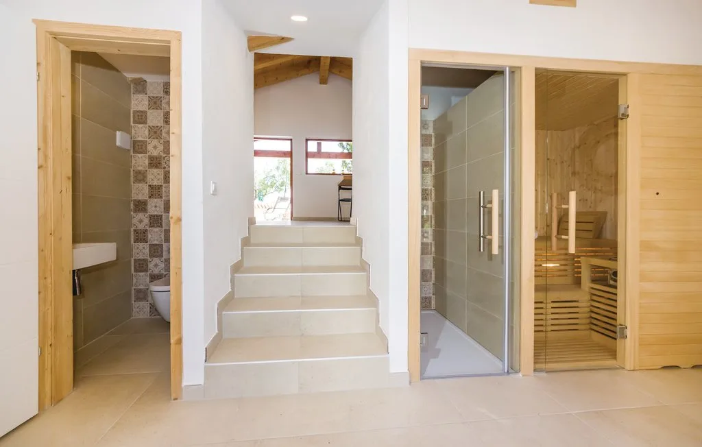 A bright interior hallway with steps between a bathroom and a glass-fronted sauna.