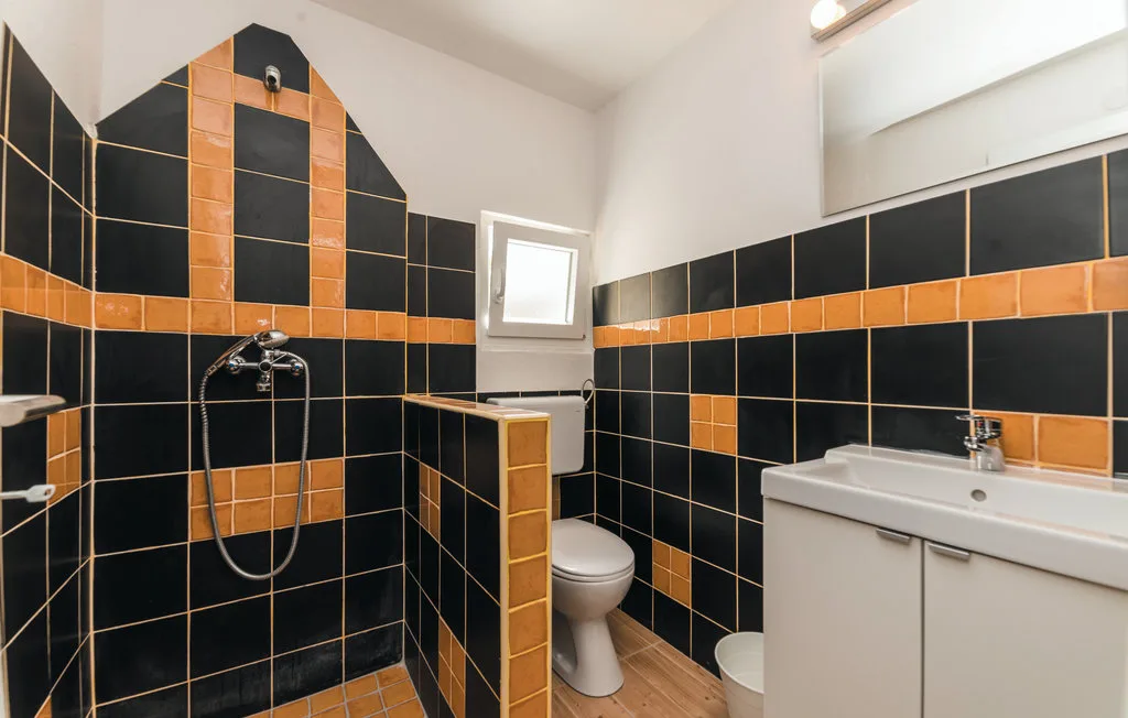 A tiled bathroom with a shower, toilet, and sink.