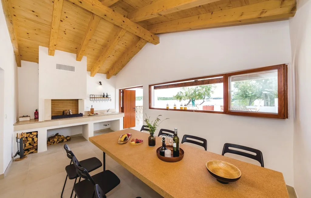A dining area with a long table beneath a wooden beam ceiling.