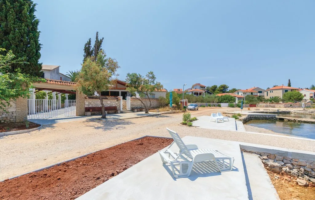 An outdoor waterfront area with paved seating and a sandy shore.