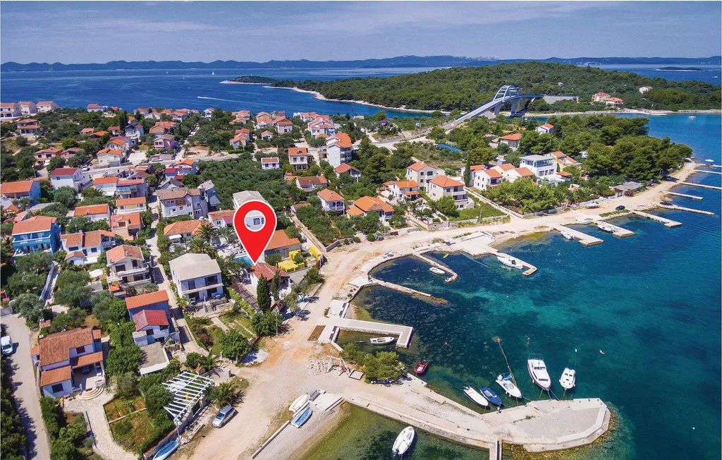 Aerial view of a coastal village beside a turquoise bay and small harbor.