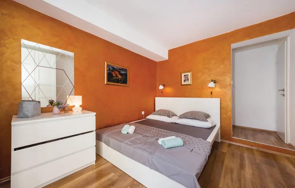 A bedroom with a double bed, bedside lights, and a white dresser.