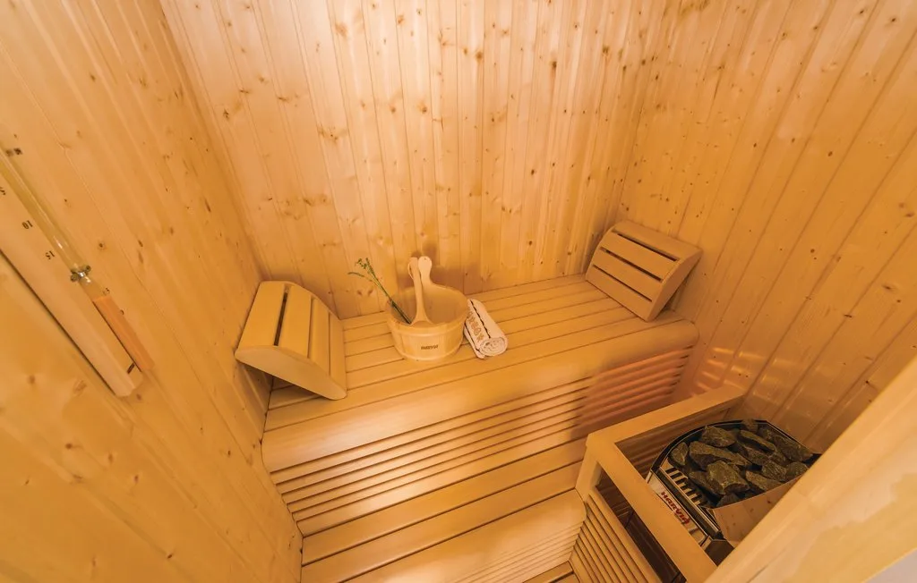 A wood-paneled sauna with a heater and wooden benches.