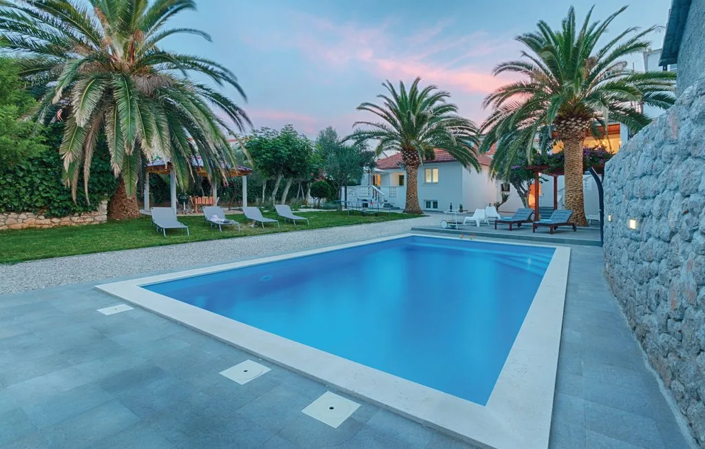 A swimming pool surrounded by palm trees and lounge seating.