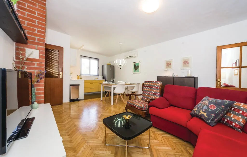 A living room with red seating, a television, and a small kitchen area.