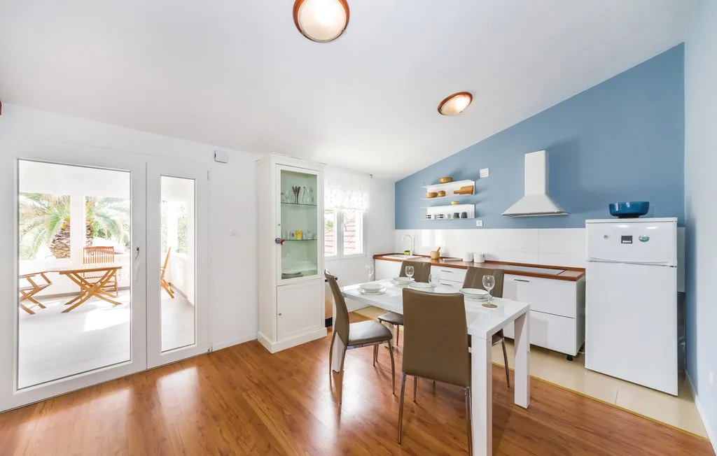 A bright kitchen and dining area with a table beside a blue accent wall.