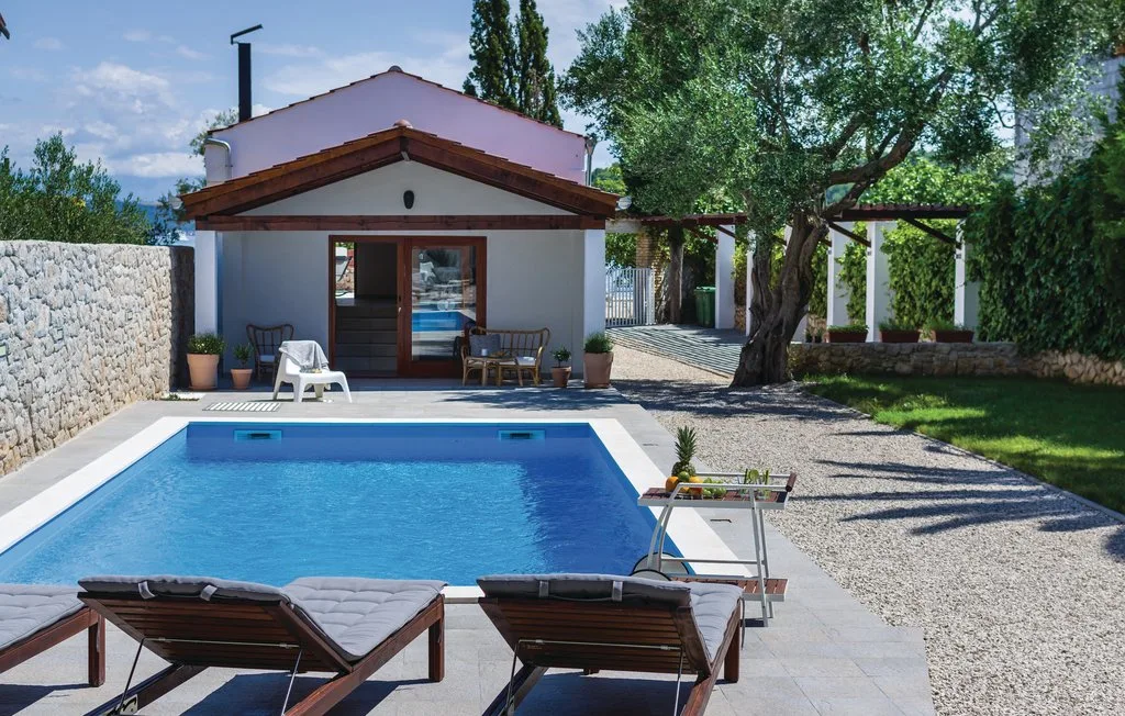 A swimming pool and patio sit in front of a small building.
