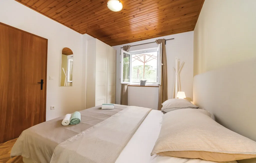 A bedroom with a bed beneath a sloped wooden ceiling and a window.