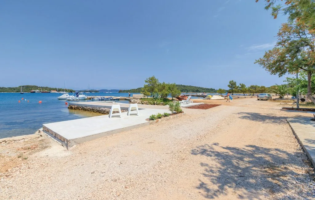 A sandy beach beside calm blue water, with boats and a small landing.