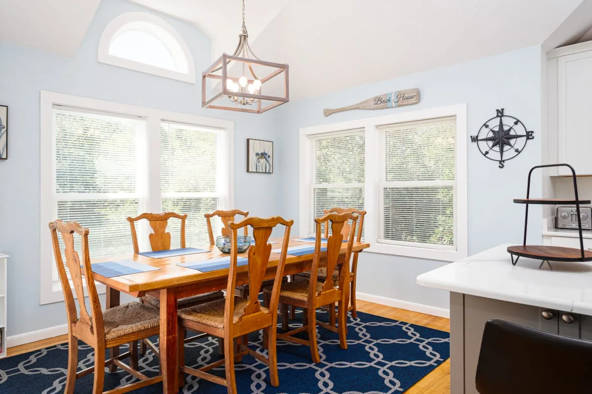 Un comedor con una mesa de madera y sillas junto a varias ventanas.