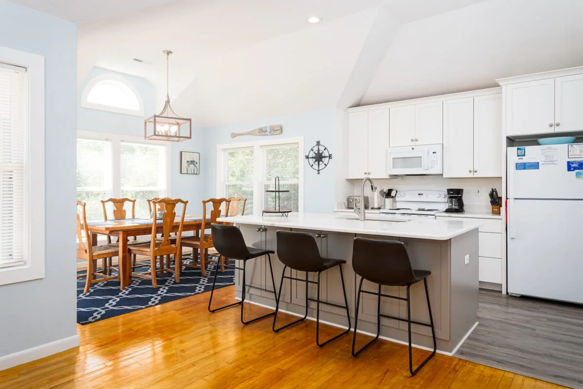 Una luminosa cocina y comedor con una isla central y una mesa de madera.