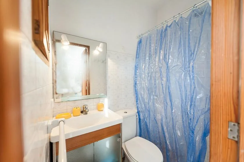 Un baño con lavabo, espejo, inodoro y cortina de ducha azul.