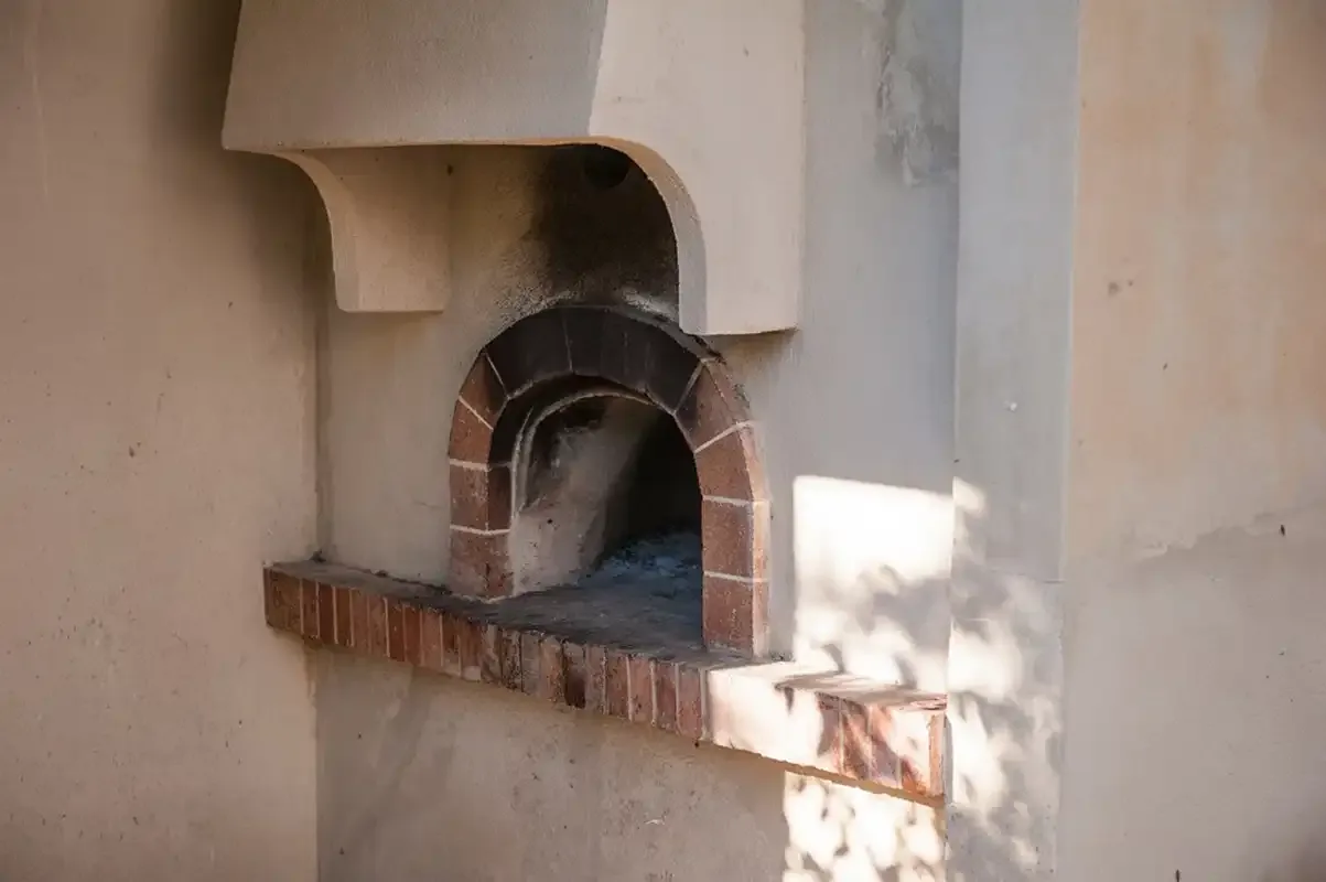 Un horno de ladrillo empotrado en una pared de yeso claro.
