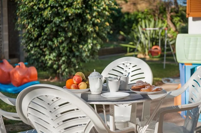 A patio dining table with cups and fruit sits among outdoor seating.