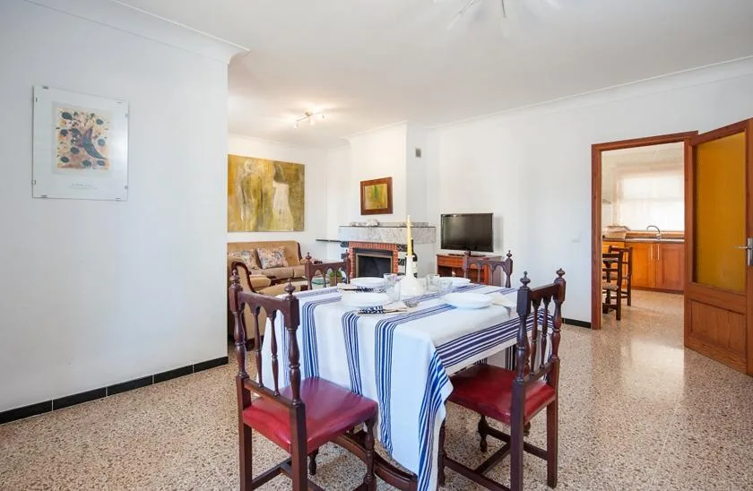 Un comedor con mesa y sillas, junto a una zona de estar.