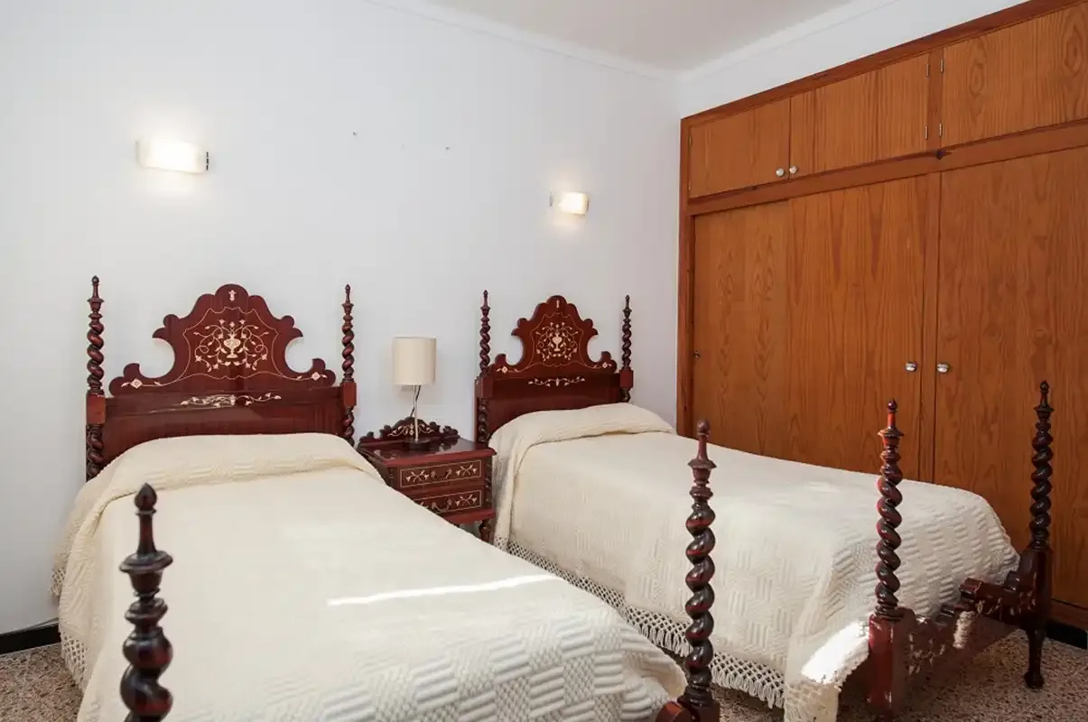 Un dormitorio con dos camas y un armario de madera.