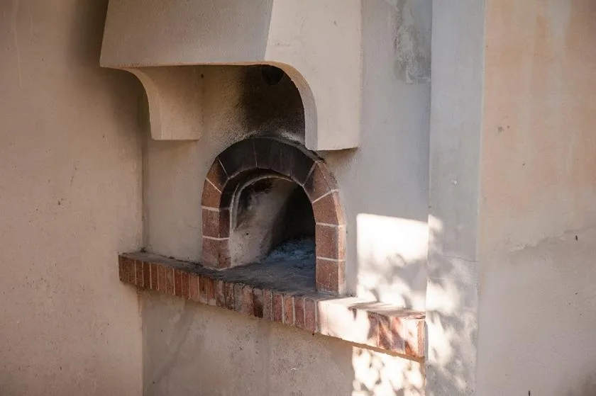 Un horno de ladrillo empotrado está integrado en una pared de yeso claro.