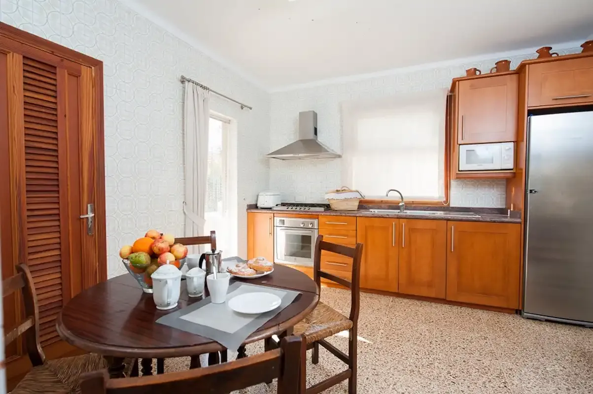 Cocina y comedor con armarios de madera y una mesa redonda.