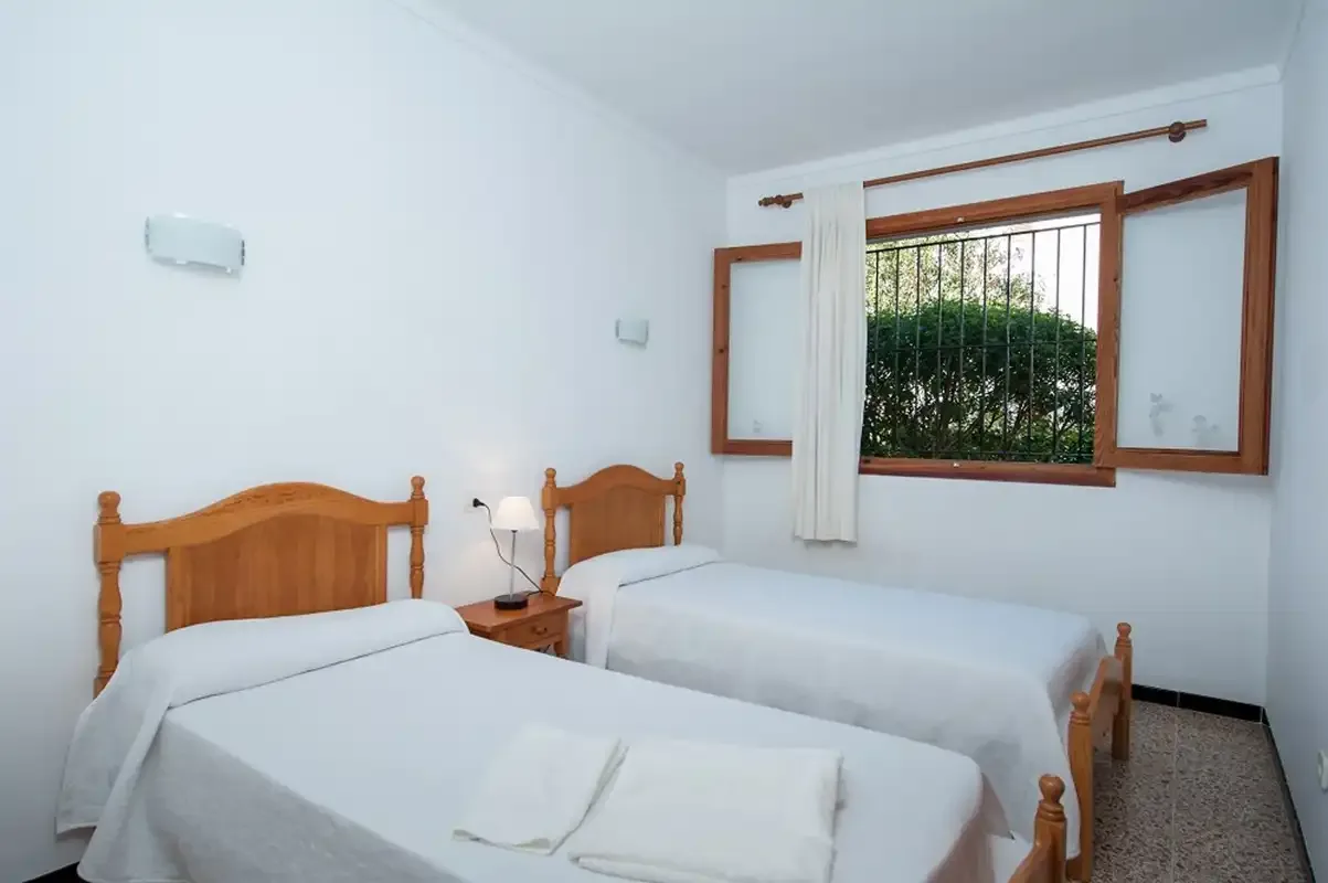 Un dormitorio con dos camas individuales y una ventana con vistas a la vegetación.