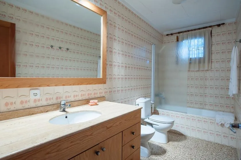 Un baño con lavabo, espejo y zona de ducha.