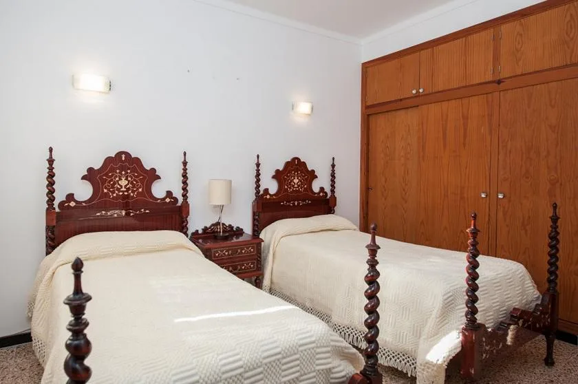 Un dormitorio con dos camas, cabeceros de madera oscura y armarios empotrados.