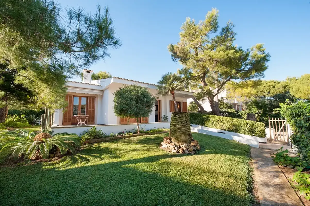Una casa de una planta está junto a un césped ajardinado y un sendero.