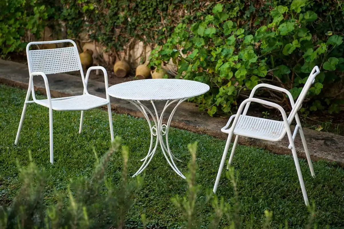 Un patio ajardinado con asientos blancos y una mesa redonda.
