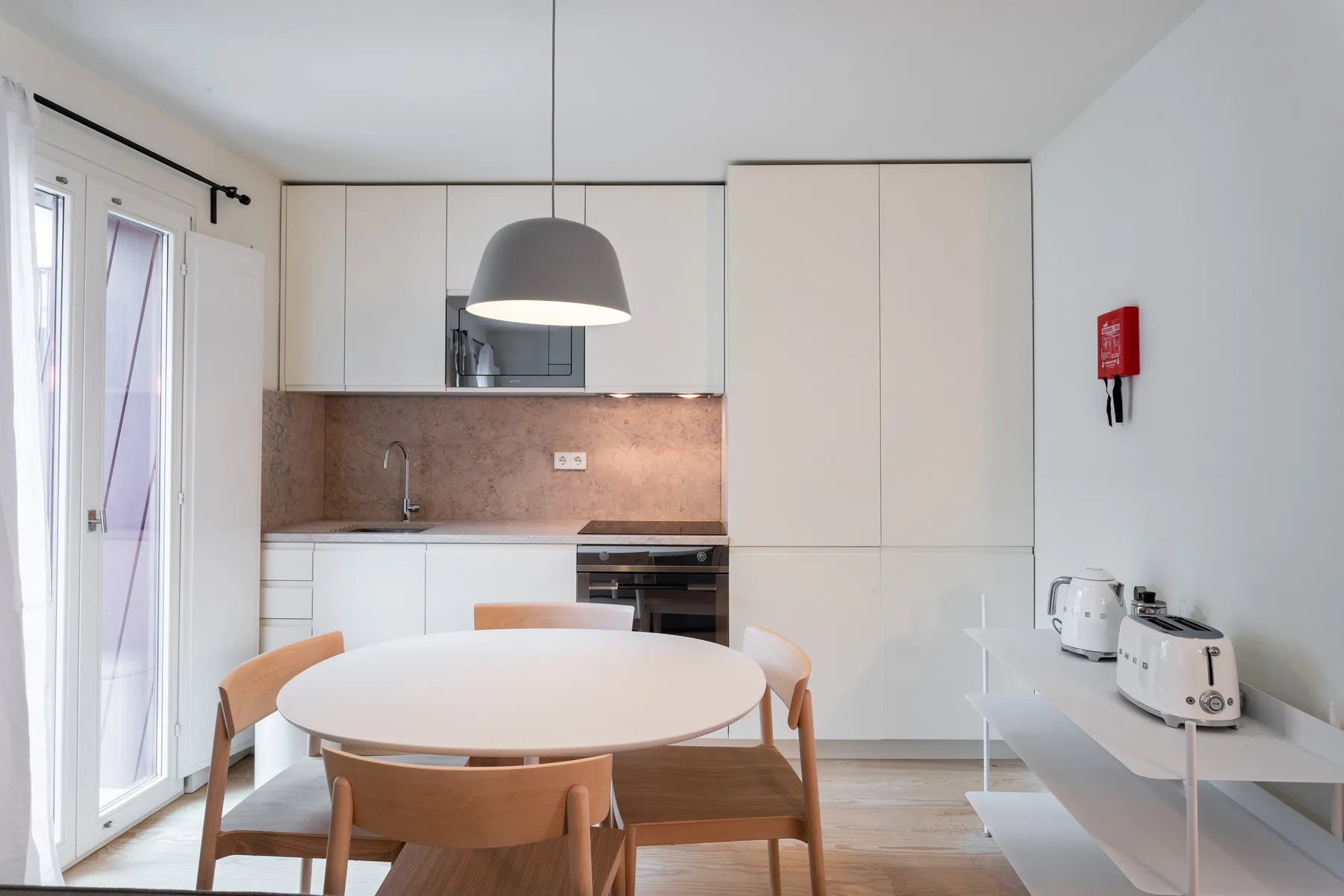 A bright dining area with a round table beside a modern kitchen.