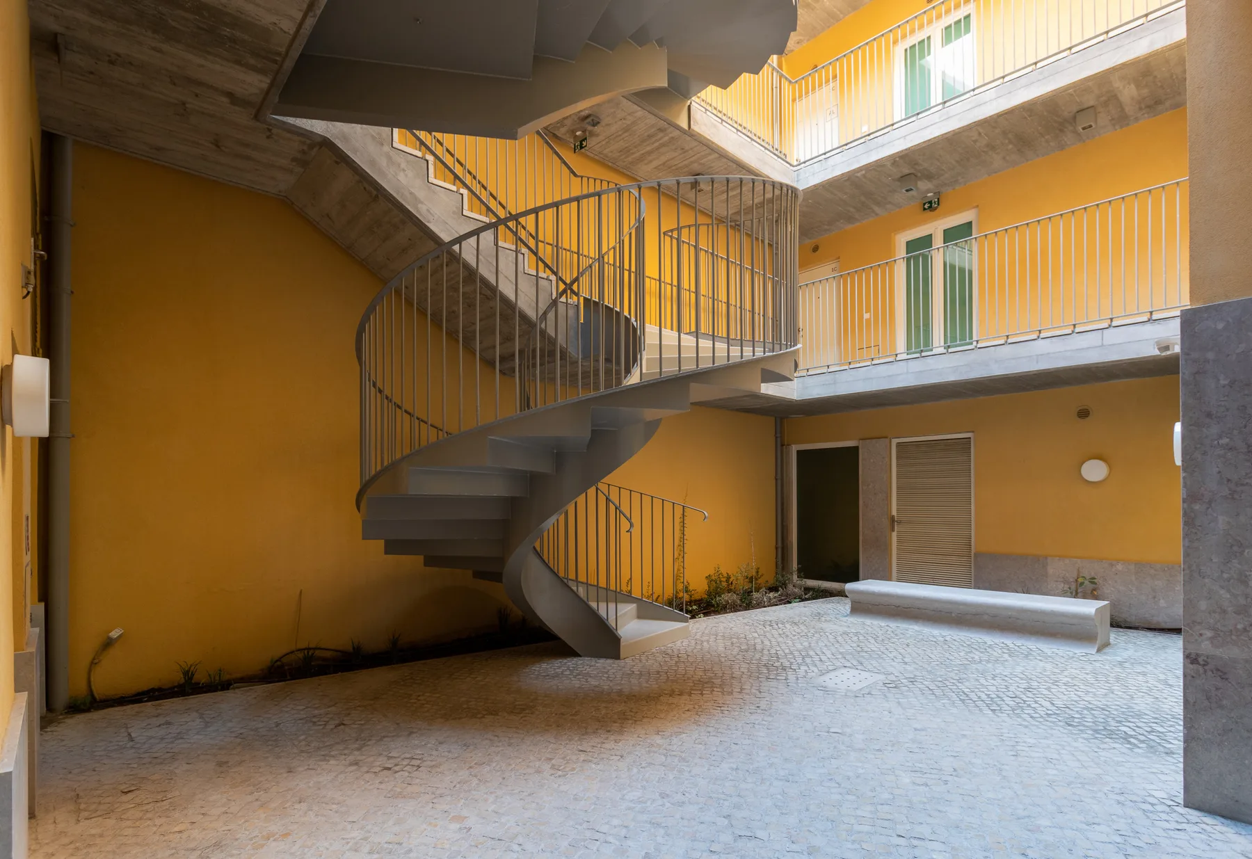 An open courtyard with a curved staircase and balconies above.