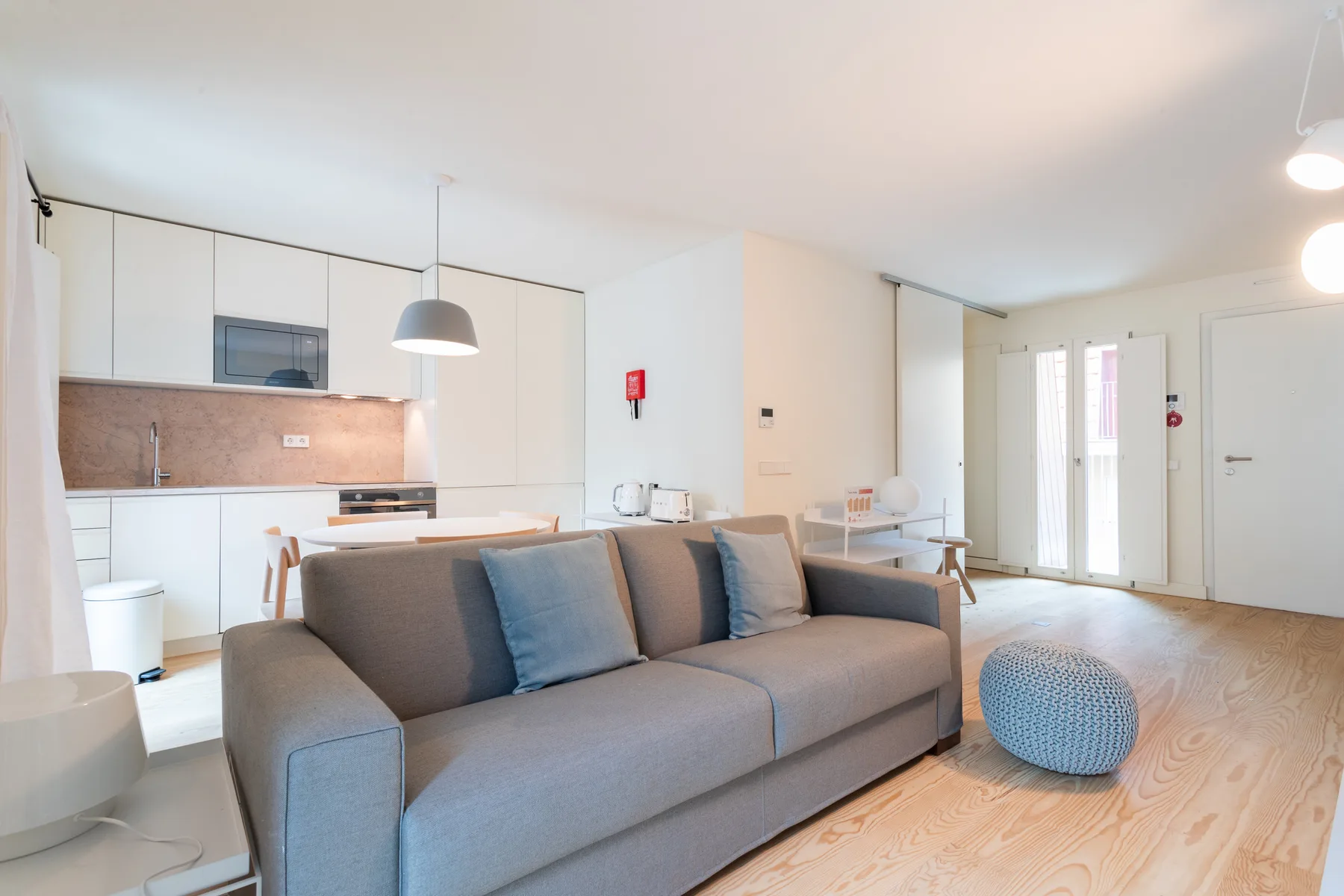 A bright living room with gray seating and an open kitchen.
