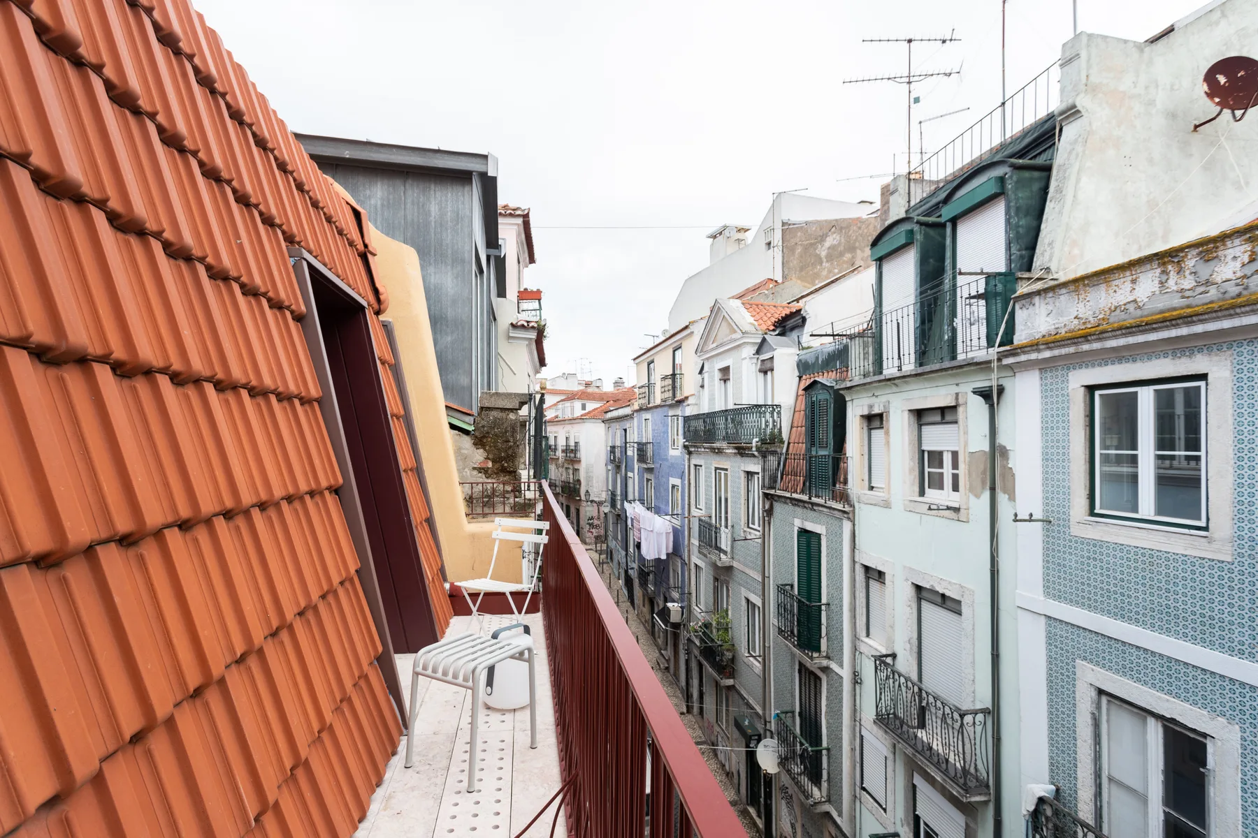 A narrow balcony overlooks closely spaced residential buildings and rooftops.