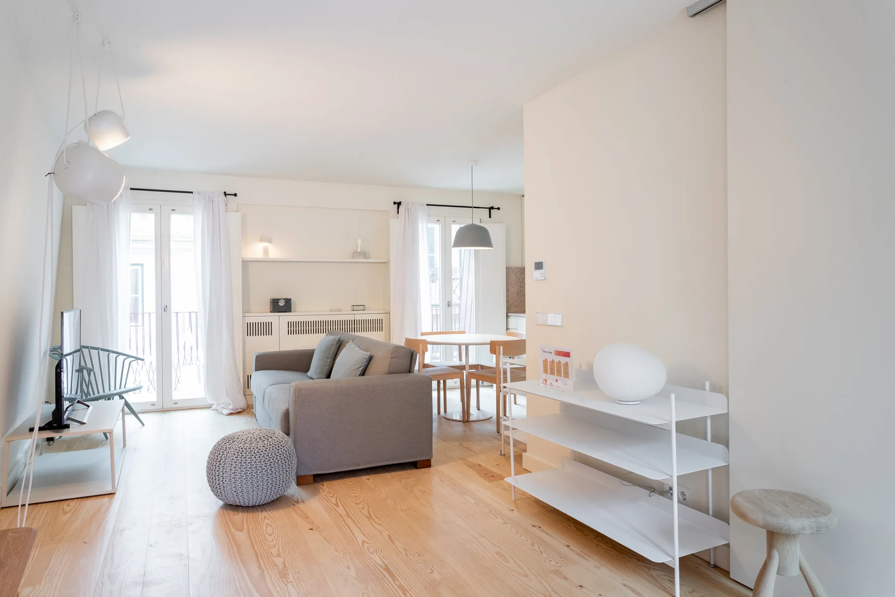 A bright living room with a sofa and dining table beside the kitchen.