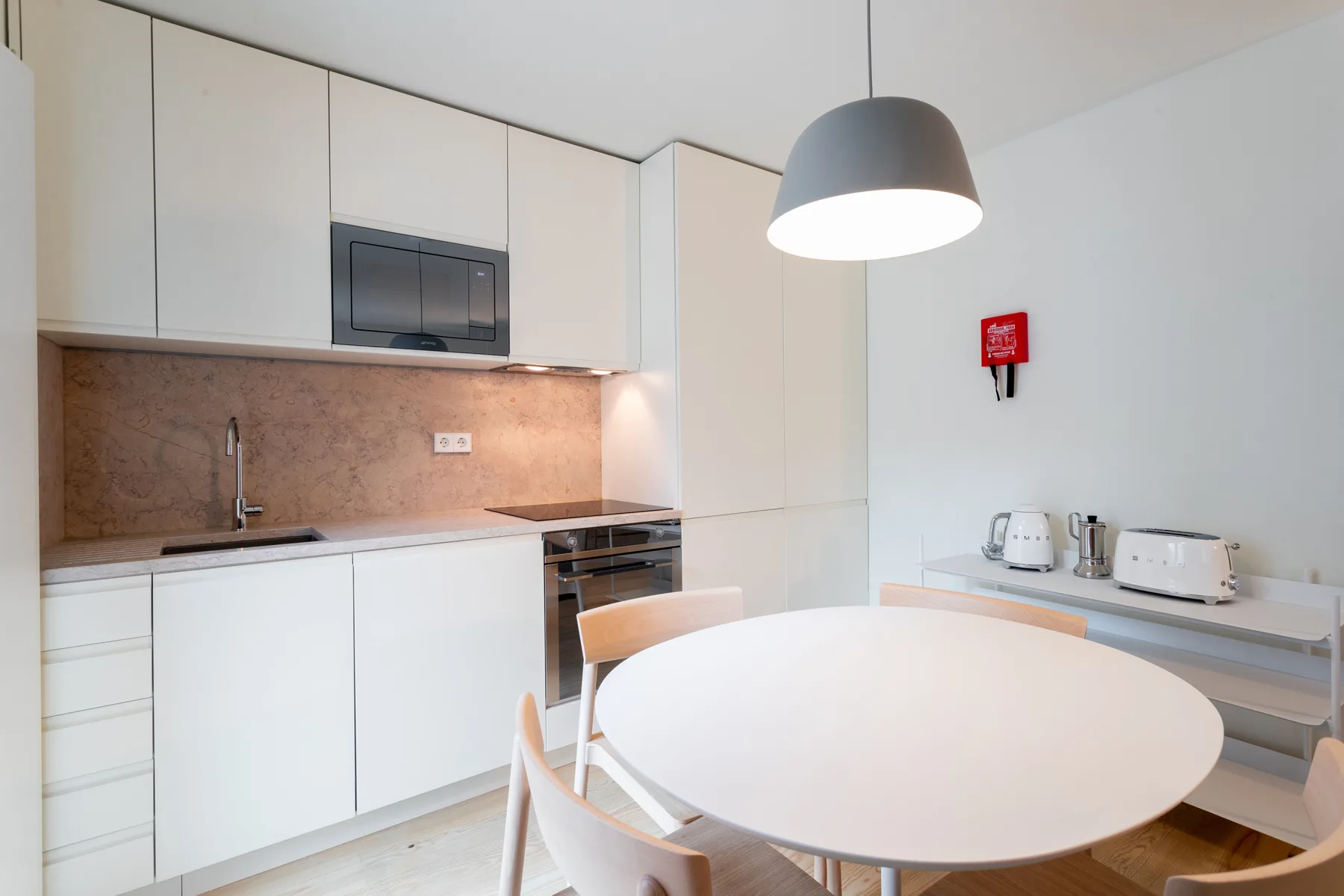 A bright kitchen and dining area with white cabinets and a round table.