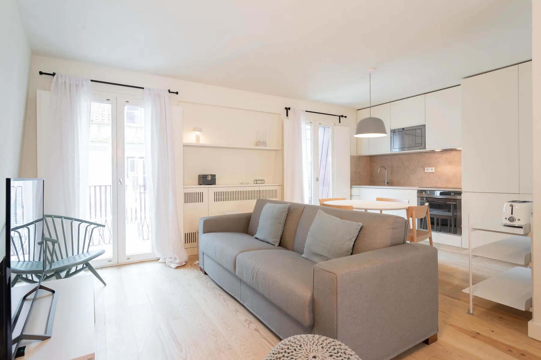 A bright living room with seating beside an open kitchen.