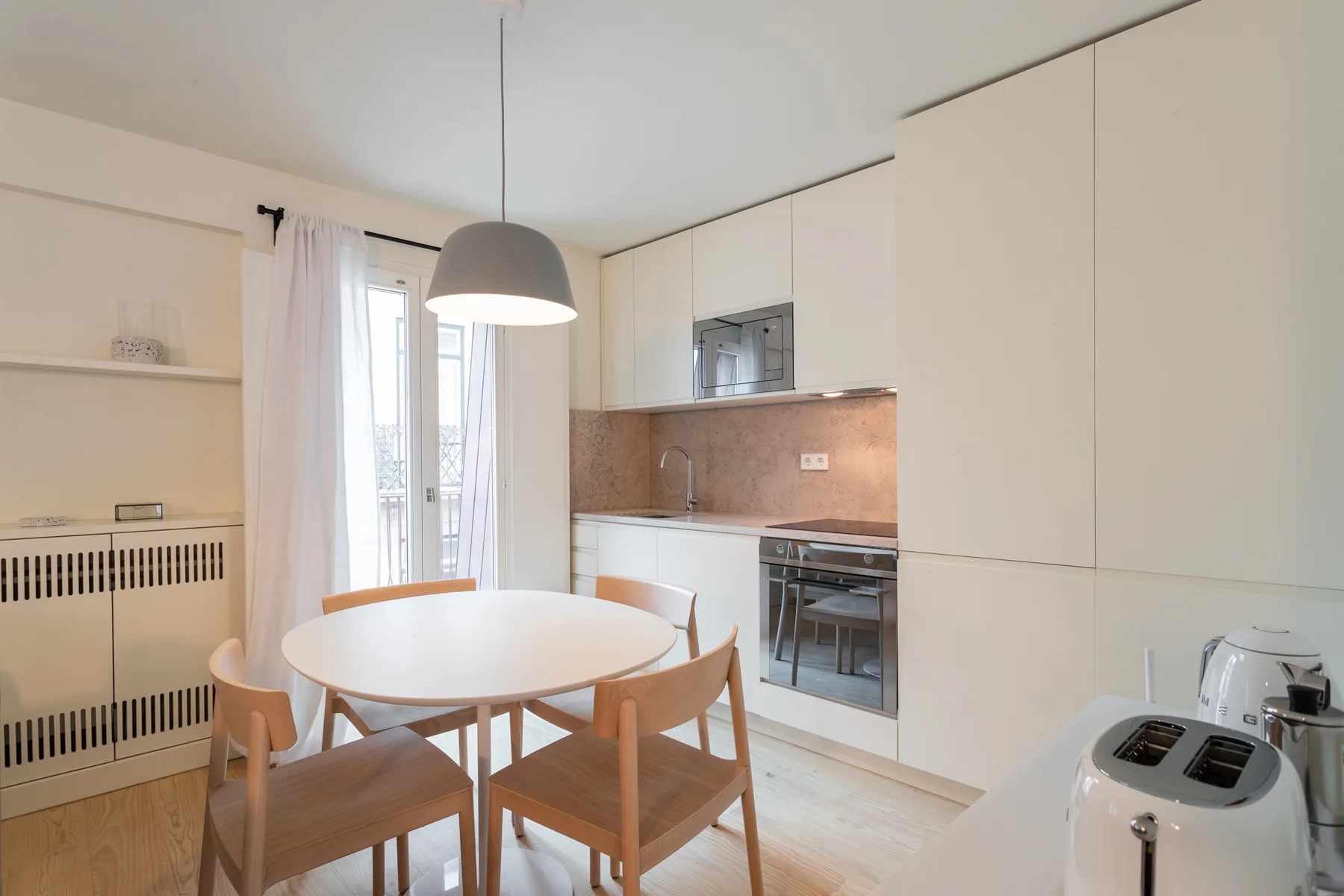 A bright kitchen and dining area with a round table beside the counter.