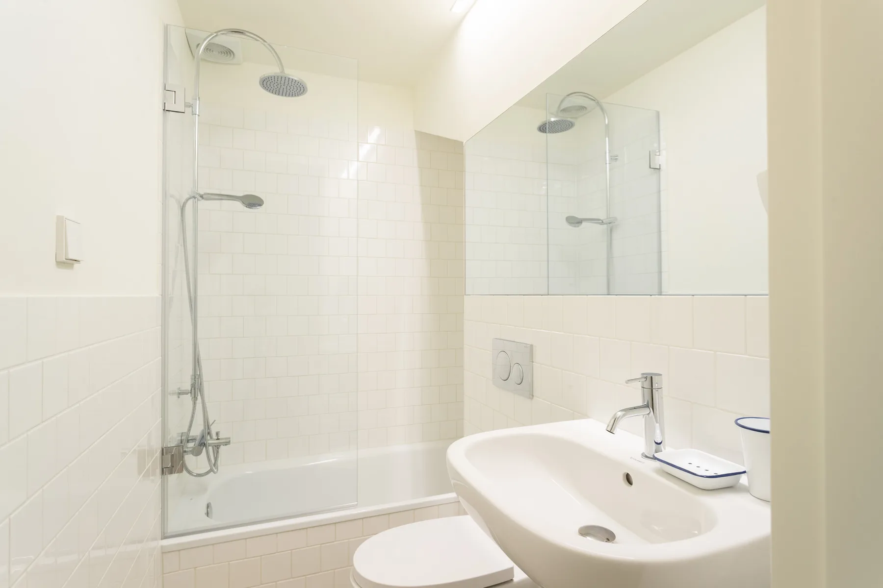 A bright bathroom with a bathtub, sink, and large wall mirror.