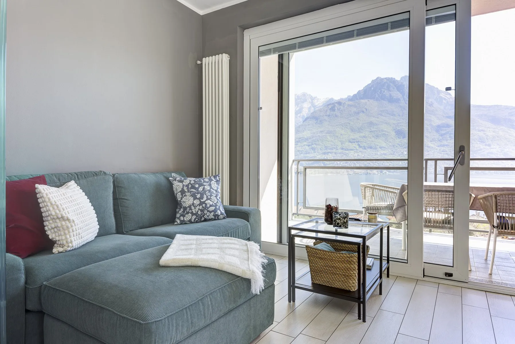 A living room with seating beside glass doors that open onto a balcony with mountain views.