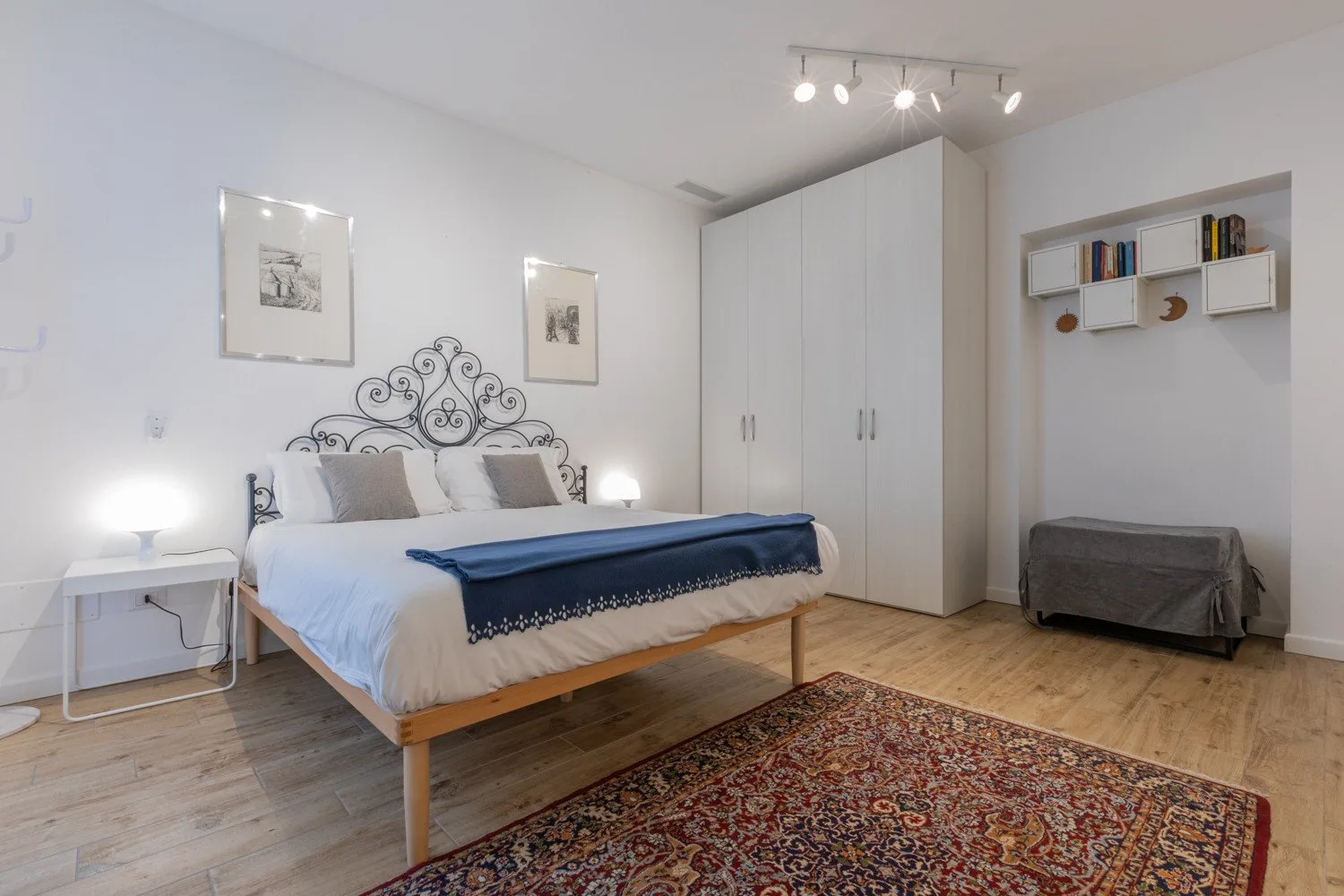 Un dormitorio con una cama, un armario y una alfombra estampada.