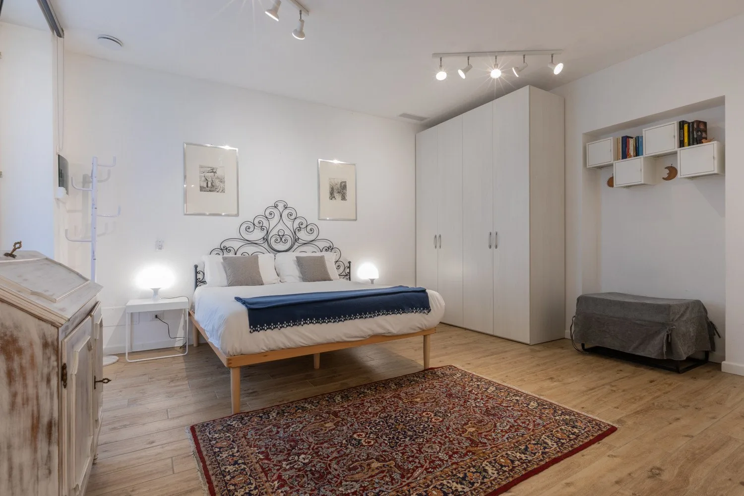 Un dormitorio con una cama, un armario grande y una alfombra estampada.