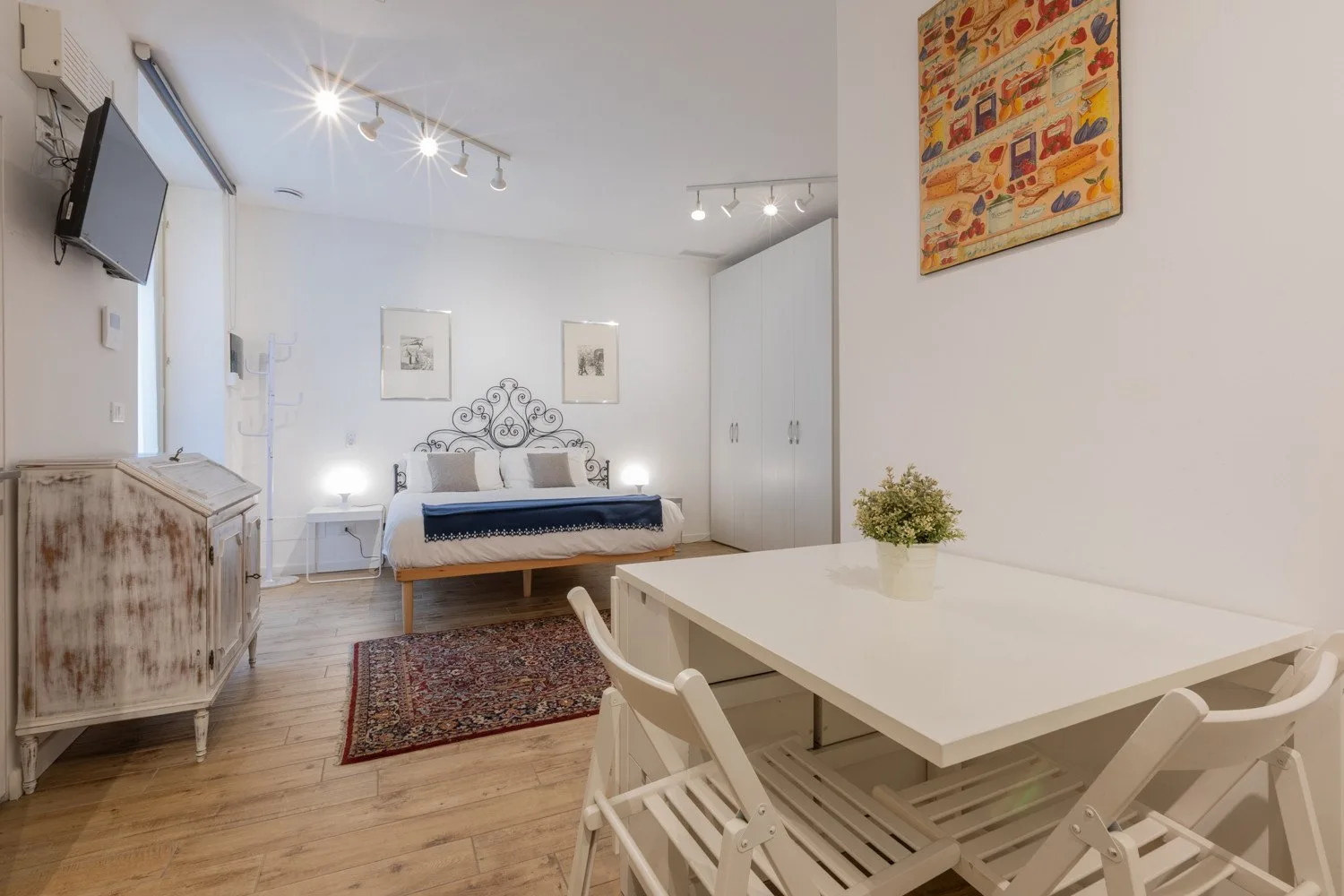 Un dormitorio luminoso con una cama, una mesa de comedor y sillas.