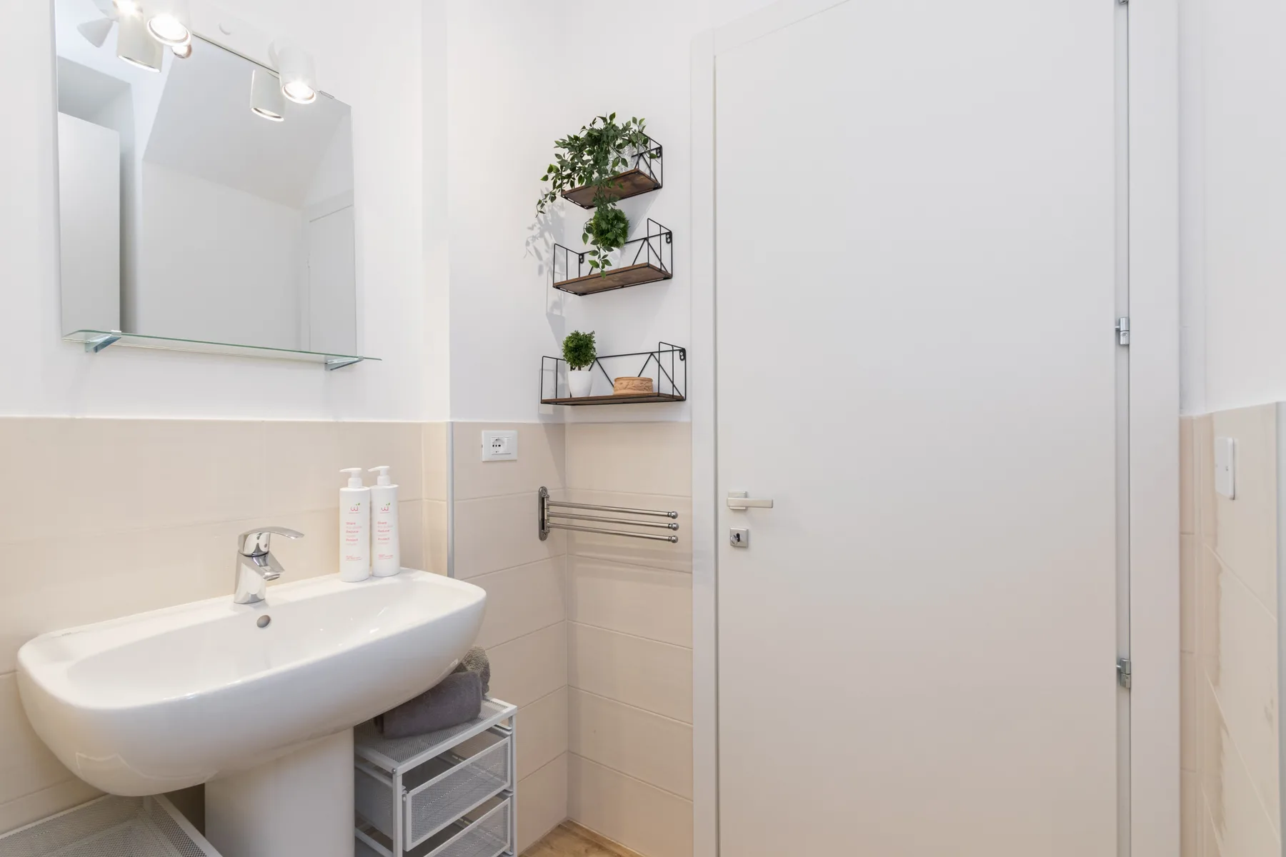 Un baño luminoso con lavabo, espejo de pared y puerta cerrada.