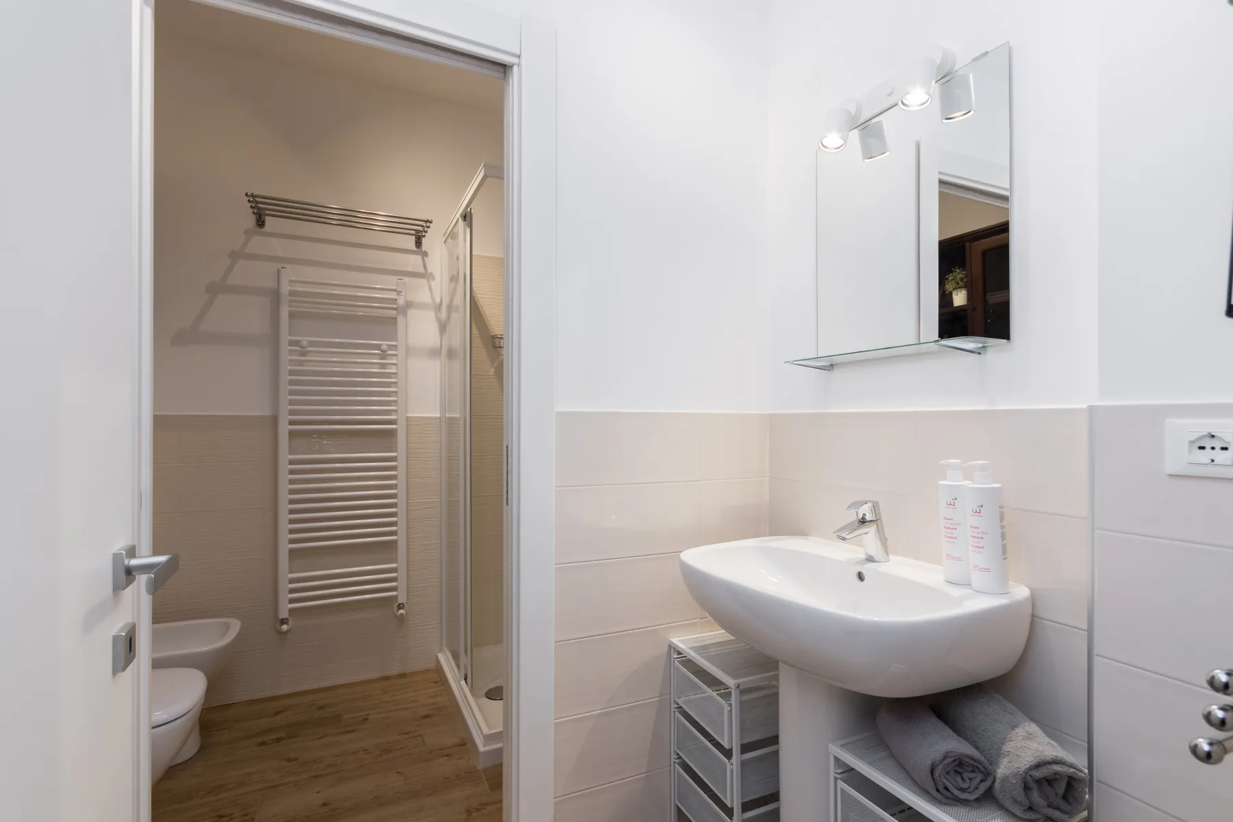 Un baño con lavabo, espejo y una zona de ducha abierta.