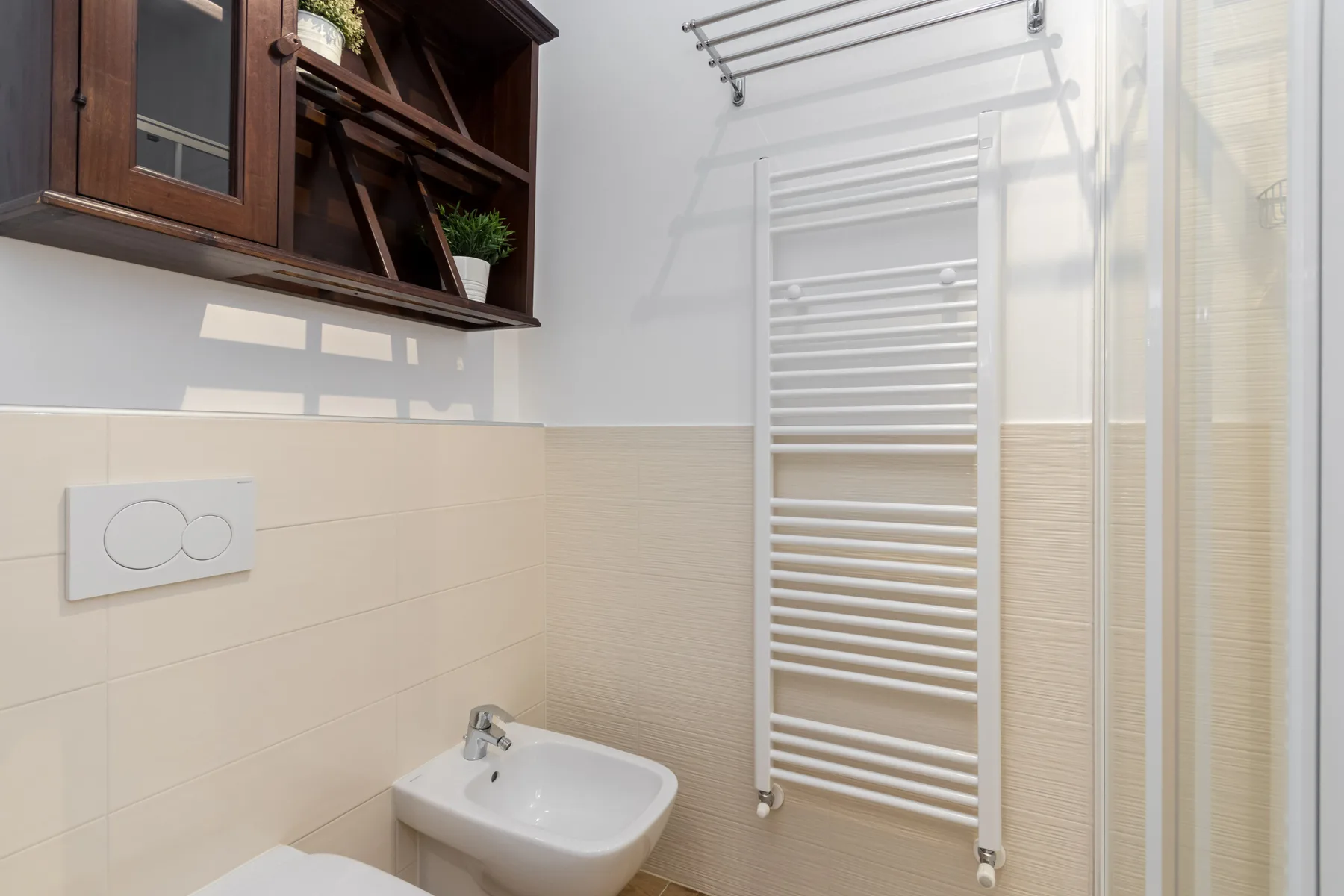 Un baño alicatado con un toallero calefactable y un bidé.